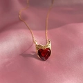 Detail der roten Herz-Zirkon-Halskette mit goldener Krone auf rosa Seidenhintergrund - Gold