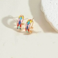 Detail of 14K gold plated hoops with colorful enamel geometric patterns on white stone - Colorful
