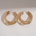 Detail view of triple-layered golden geometric C-shaped hoop earrings on textured surface - 925 Silver Needle / Large / Gold