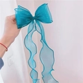 Detail of a large blue organza bow hair clip with elegant long wavy ribbon streamers - Teal