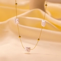 Detail of gold chain necklace featuring three white baroque pearls on silk fabric - Square Pearl