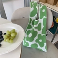 Detalle del bolso de punto con flores verdes y blancas y textura tejida en una silla - Verde