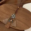 Detail van boheemse bloemenhanger met beige kwastjes en houten kralen op houten dienblad - Koffie Bloem Kwastje Stijl (1# Ketting)