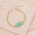Detail of gold curb chain bracelet with green enamel Gemini zodiac pendant and zircons - Gemini