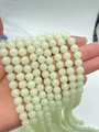 Detailed view of hand-held glowing round beads in a natural pale green jade-like finish - 6mm (Approx. 60pcs) / Light Green Luminous Stone