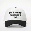 Détail de la broderie du texte « put it on my husband's tab » sur une casquette noir et blanc - Taille unique / Blanc et Noir