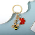 Golden bee keychain with sparkling crystal wings and a red hexagonal honeycomb charm - Red (E)