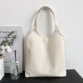 Detail of minimalist beige canvas tote bag with wide shoulder straps on a display stand - Beige