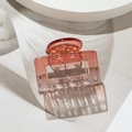 Detail view of a small square transparent hair claw clip with amber gradient finish - Square Red