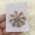 Elegante spilla a fiore dorata con perle bianche e cristalli su sfondo in peluche - Fiore di perla radiante