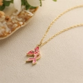 Golden necklace with pink enamel butterfly ribbon pendant on a natural background - Pink Ribbon Butterfly