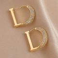 Detail of gold letter D earrings with white zircons on a luxury champagne silk background - Gold Zircon Letter D Earrings / Gold
