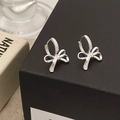 Close-up of polished silver bow-shaped hoop earrings on a textured black gift box - Silver Bow Knot Hoop Earrings