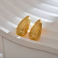 Makroaufnahme goldener Tropfenohrringe mit unregelmäßiger vertikaler Metallstruktur - Tropfenform / Roségold