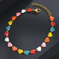 Primer plano de pulsera dorada con dijes de corazones de esmalte y cierre de mosquetón - Corazón