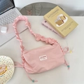 Pink pleated shoulder bag with bow detail shown in a stylish lifestyle setting - Light Pink