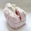 Primer plano del neceser acolchado con flores rosas, cremallera y espacio interior - Rosa
