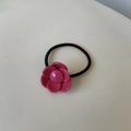 Detail of a pink camellia resin flower charm on a black elastic ponytail holder - Rose Red Solid