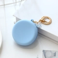 Light blue round silicone coin purse with gold zipper and keychain on white desk - Blue