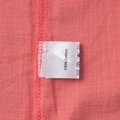 Detail view of 100% cotton fabric with neat stitching and clothing care label on pink shirt - 100% Cotton
