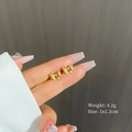Detail of 4.2g golden bow stud earrings being held to show 1x1.2cm size and texture - Gold
