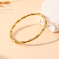 Detail view of a vintage golden bamboo style bracelet on a minimalist textured background - Gold Bamboo Style (S102)