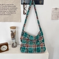 Détail du sac en toile à carreaux marron vert avec bouton bois et texture rétro - Vert