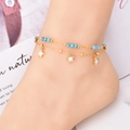 Double-layered turquoise bead anklet with gold chain and white star pendants on model - Star Style