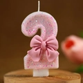 Pink glitter number 2 birthday candle with a decorative bow for party celebrations - Number 2