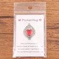 Red Pocket Hug heart pendant with vintage silver border and greeting card on wood background - Vintage Border Red Heart