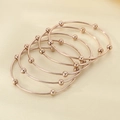 Dettaglio di cinque bracciali rigidi oro rosa con perle lucide su fondo di seta - Diametro interno 60mm / Set di 5 Anelli / Oro rosa