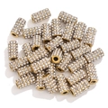 Close-up of golden cylindrical DIY beads with sparkling rhinestones on white background - White