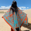 Châle bohème orange et turquoise à motifs cachemire et franges dans un décor désert - Motif fleur sacrée
