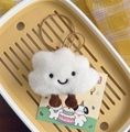 Detailed macro view of white fluffy cloud plush keychain with cute smiling face embroidery - White