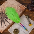Rainbow metal pen with vibrant emerald green feathers on a vintage wooden desk - Green