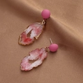 Detail of pink resin earrings with faux agate slices on brown textured fabric background - Pink