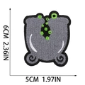 Detail showing grey cauldron embroidery patch with green bubbles and 6x5cm measurements - Letter U