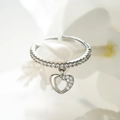 Macro shot of silver open ring with pave-set crystals and a dangling hollow heart charm - Adjustable Open / Silver