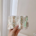 Detailed view of floral canvas pouch with green braided rope zipper and woven label - Orange Striped Floral Coin Purse