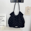 Dettaglio della borsa tote nera trapuntata con fiori appesa a una parete minimalista - Chiffon Piccoli Fiori Nero