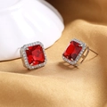 Macro detail of octagonal square red gemstone stud earrings with silver halo on gold satin - Red