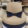 Detalle de sombreros de paja apilados en caqui y negro con decoración de lazo - Estilo Lazo / Caqui