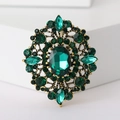 Vintage bronze brooch featuring an oval green gemstone and rhinestones on a white base - Dark Green