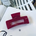 Close-up of deep red resin rectangular claw clip on a white book with aesthetic green plant - Rose Pink