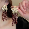 Detail of vintage gold leaf earrings with long dark red beaded tassel fringe clusters - Gold Leaf Red Tassel Style