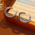 Detailed view of C-shape hoop earrings with multi-color zircons on a wooden tray - Silver - Rainbow Color (Silver Needle)