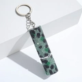 Macro detail of silver keychain featuring a sparkling green pixelated creeper design - C18-Green Pixel