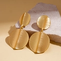 Macro detail of golden geometric earrings featuring brushed metal texture and linked circles - Brushed Double Disk Design / Gold
