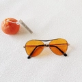 Detail of aviator kids sunglasses with orange lenses and slim metal frame on white surface - Orange