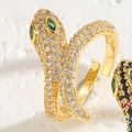Macro detail of a 14K gold snake ring featuring green gem eyes and pavé zircon stones - Adjustable Open / Gold White Zirconia